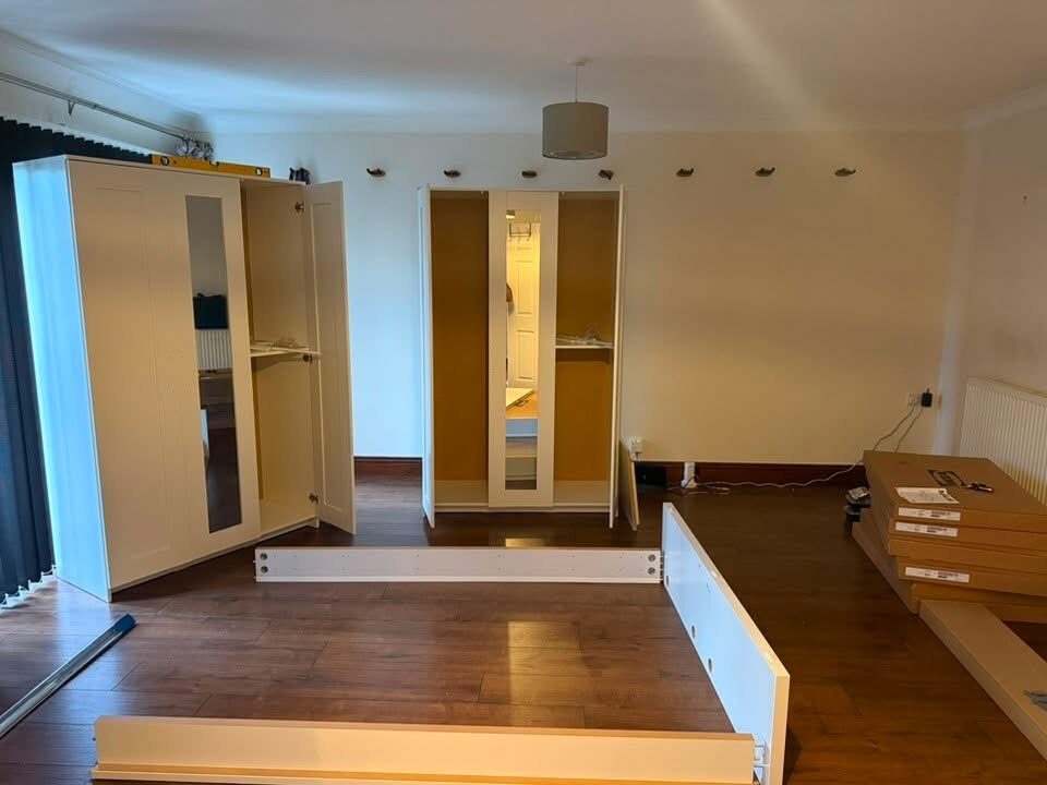 Bedroom mid-fit with two wardrobes assembled and bed frame in progress